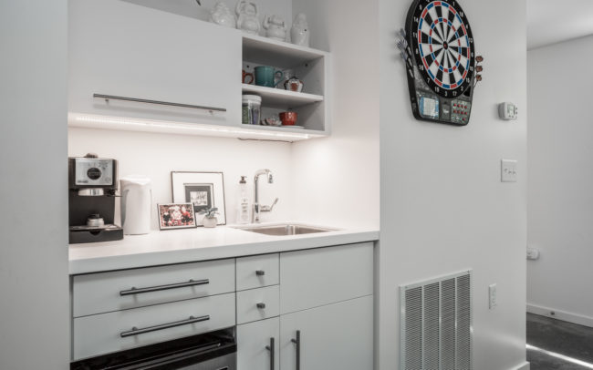 A small kitchen with white cabinets and a dart board.