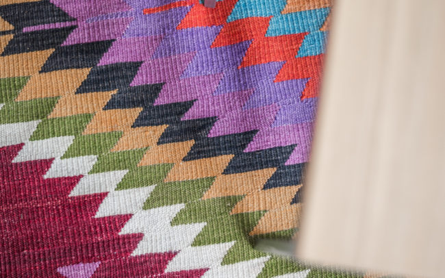 A colorful kilim rug on a wooden floor.